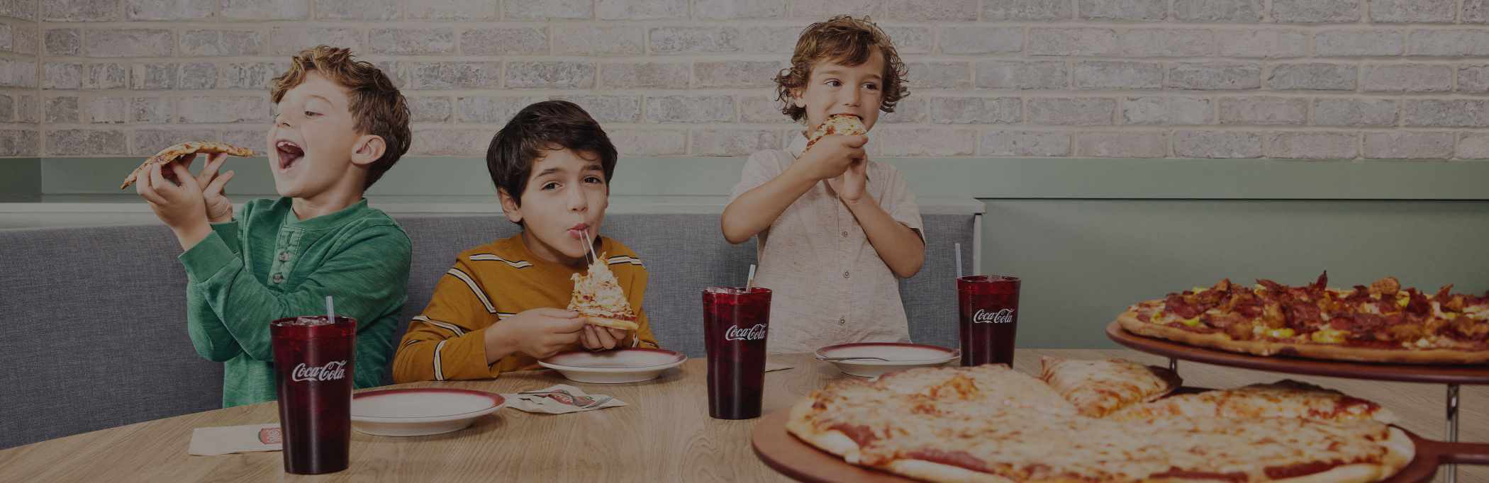 Three young boys enjoying LaRosa's pizza.